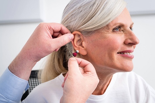 Ältere Frau erhält ein Hörgerät zur Verbesserung des Hörvermögens beim Hörakustiker.